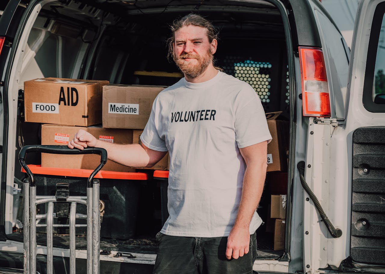 services-02 Volunteer standing by a van loaded with aid supplies, ready to serve the community.
