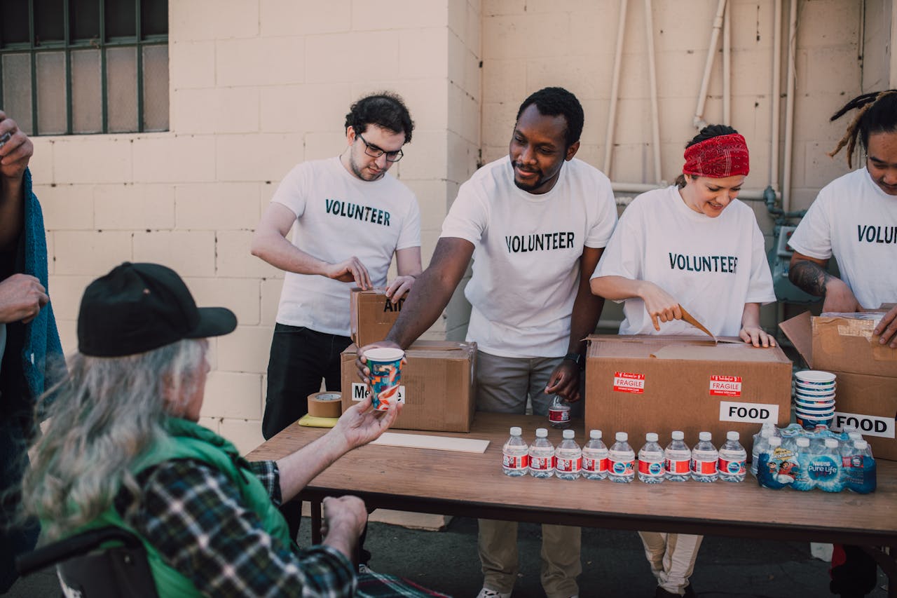 who-we-are Volunteers distribute food and drinks to the needy at an outdoor charity event.