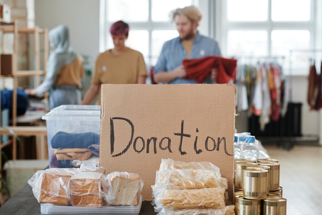 team-01 Volunteers sort clothes and food in a donation center. Cardboard sign reads 'Donation.'