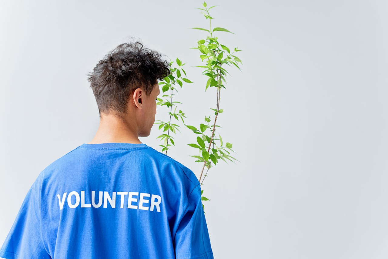 journey Young volunteer in blue shirt nurturing plant, symbolizing eco-friendly initiatives.